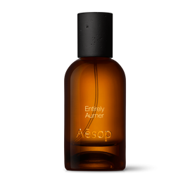 Amber glass Aesop Entirely Aurner Eau de Parfum bottle with black cap on a white background.