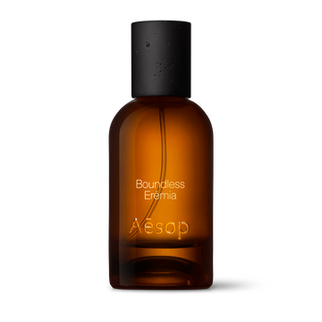 Amber glass Aesop Boundless Eremia Eau de Parfum bottle with black cap on a white background.