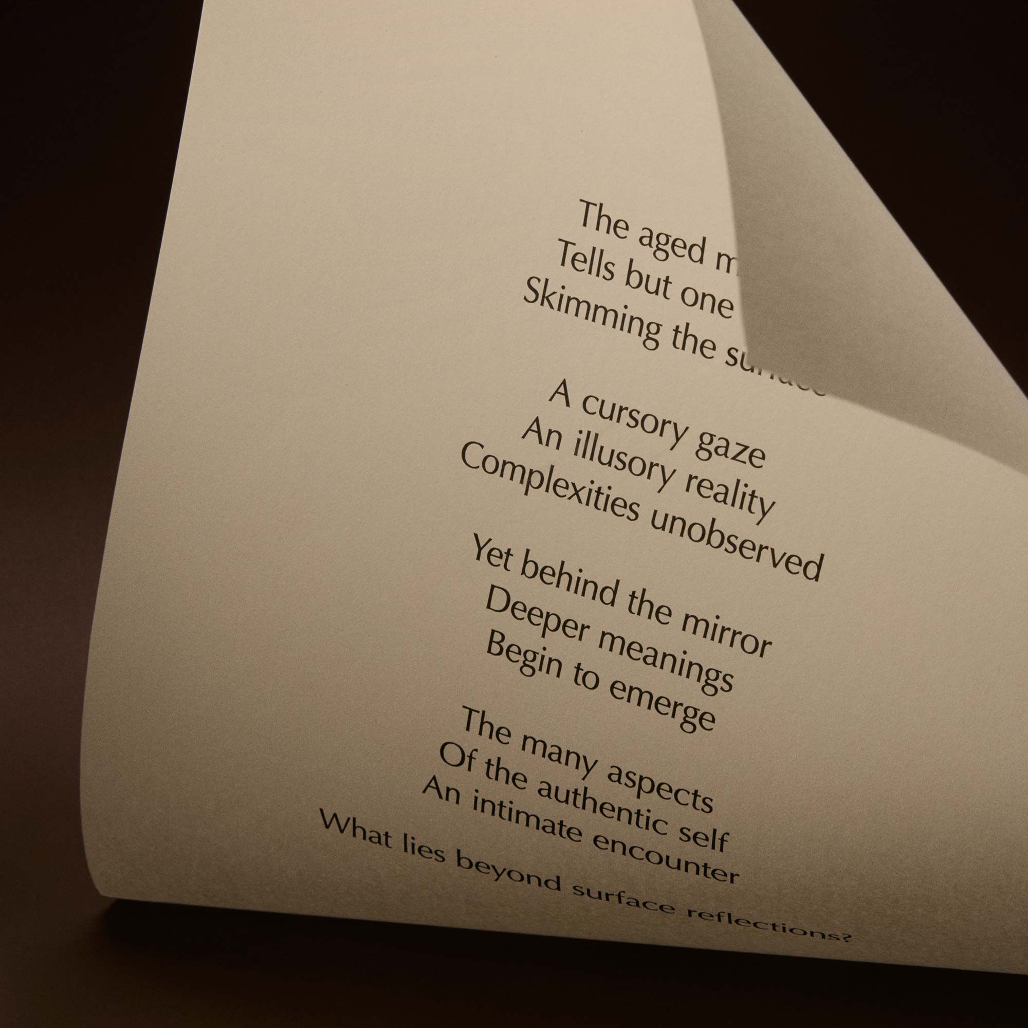 Curved cream page with printed verse against a dark brown background.