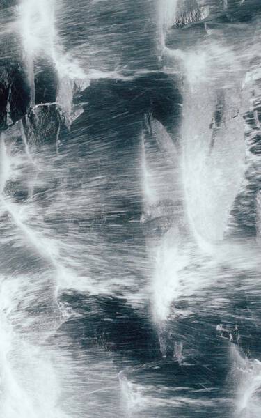 Dark blue-grey rock surface with white vein-like streaks and rough mineral texture, forming a high-contrast marbled pattern.