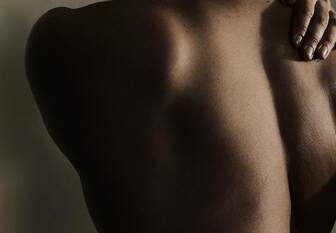 Person's bare back with one hand resting on their shoulder.