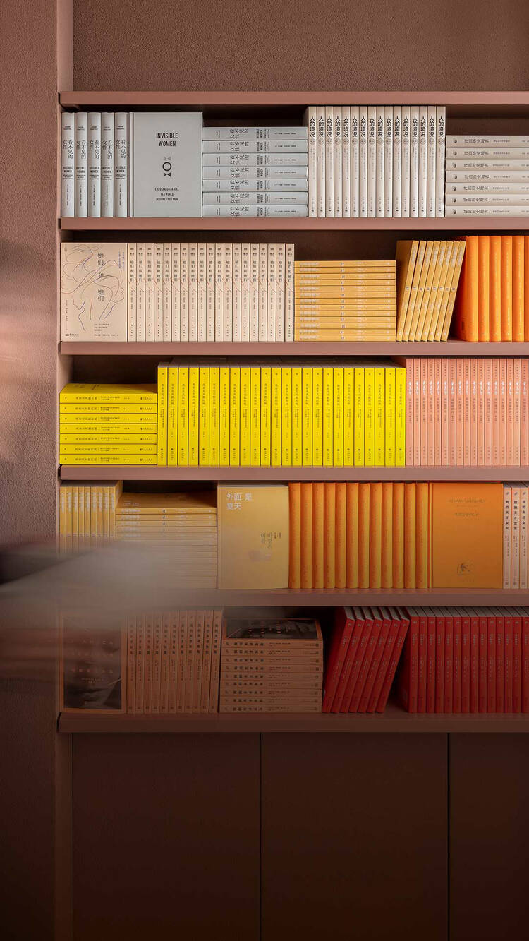 Small row of colourful books on a dark maroon shelf beside ribbed columns.