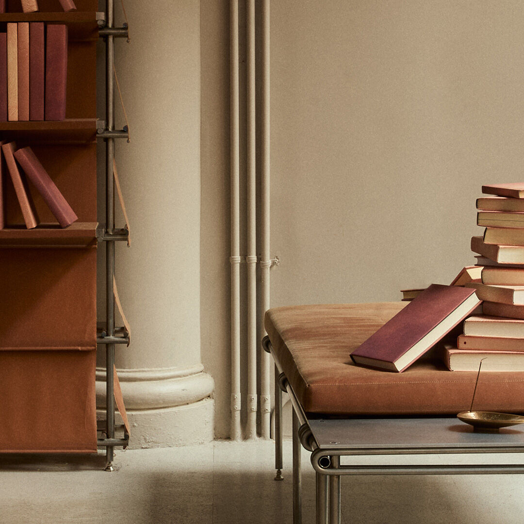 Stacks and rows of colourful books displayed on a pale table before dark ribbed shelves.