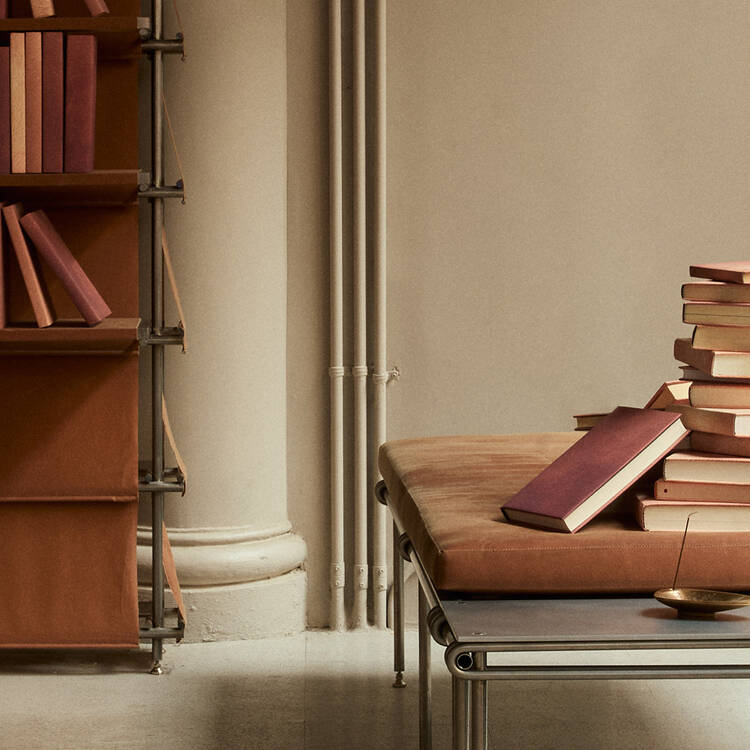 Stacks and rows of colourful books displayed on a pale table before dark ribbed shelves.